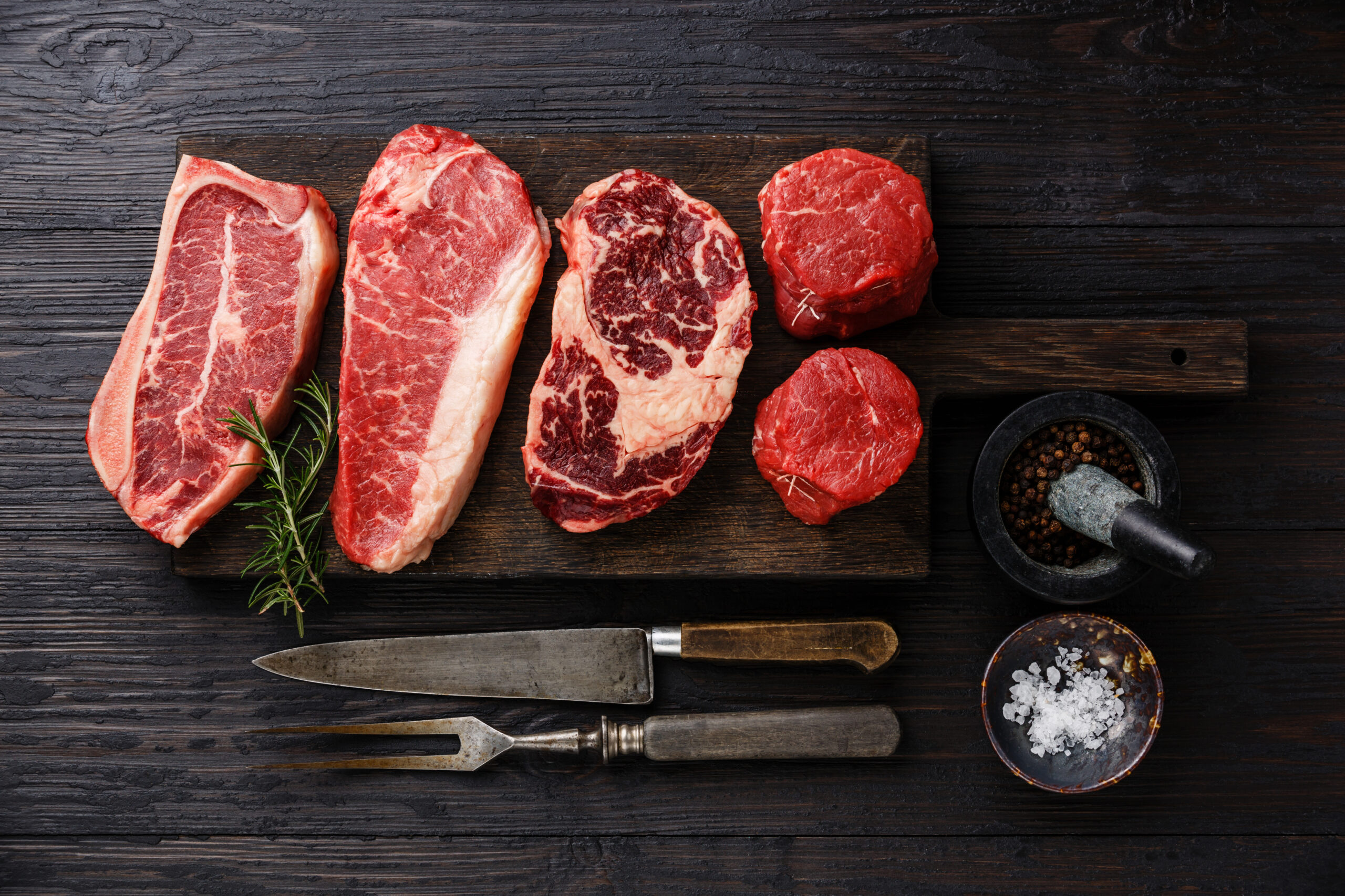 Succulent pulled pork on a wooden cutting board, showcasing tender, shredded meat with a crispy outer layer. A fork rests beside the meat, highlighting its juicy texture and rich seasoning.